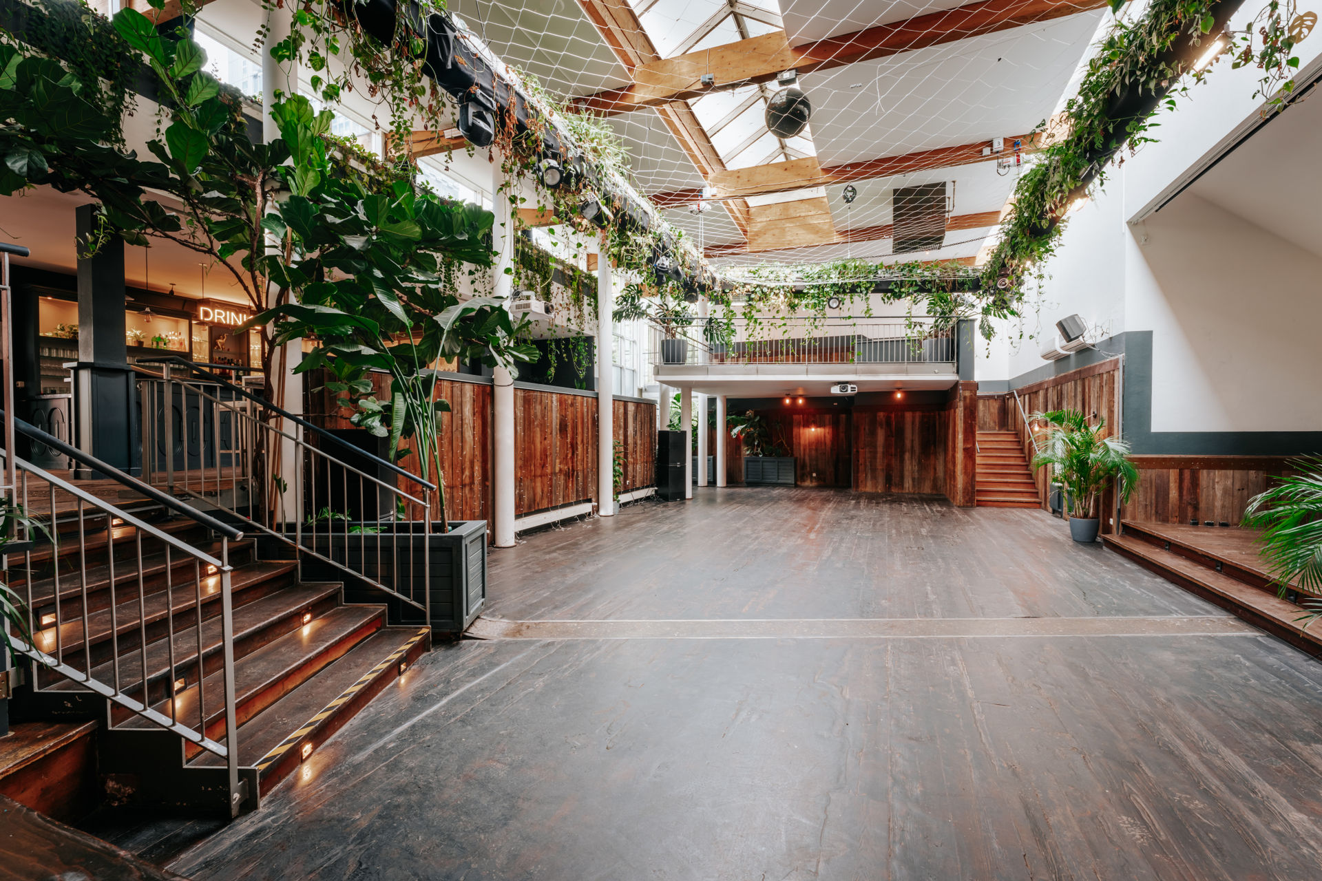 Das leere Atrium unter dem Glasdach — Galerien über drei Ebenen, Bar links, Podest rechts