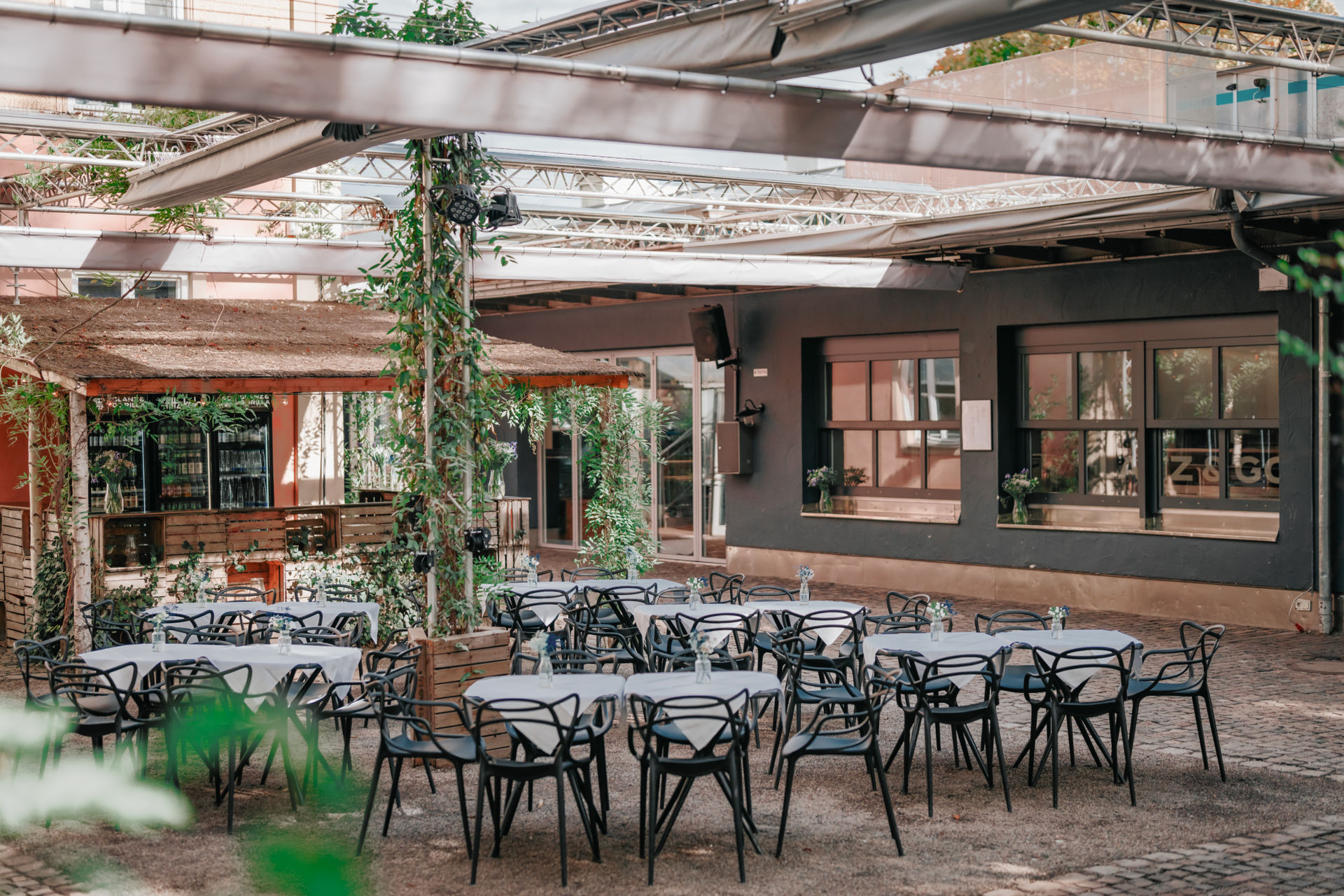 Überdachte Terrasse mit Traversendach und Planen, runde Tische, eigene Außenbar